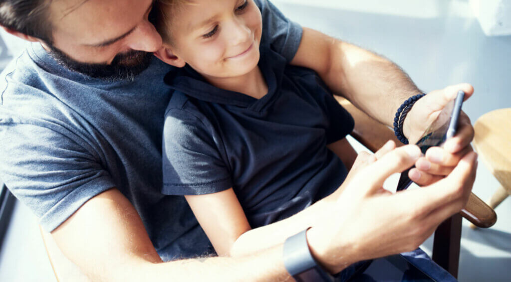 Boy with father, looking at their phone